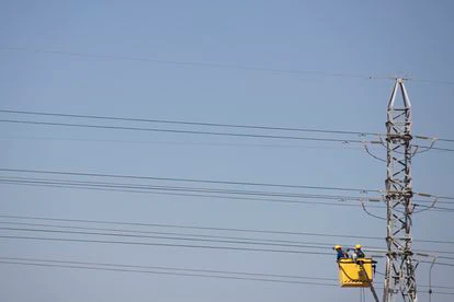 Dos operarios trabajan en un tendido eléctrico a las afueras de Sevilla.