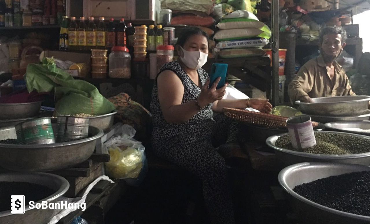 Una foto de un comerciante en Vietnam mirando un teléfono inteligente