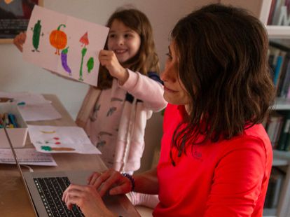 Una mujer teletrabaja junto a su hija en Madrid.