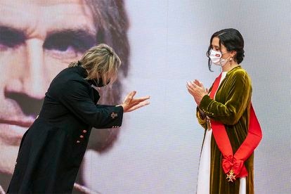 El artista Nacho Cano entrega a Isabel Díaz Ayuso la gran cruz del Dos de Mayo después de que esta le condecorara en la sede de la Comunidad. "Por ser tan buena presidenta, la medalla te la mereces tú", le dijo.