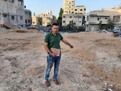 El librero Shaban Eslim señala el lugar donde se encontraba su librería, destruida por los bombardeos israelíes, con un Corán rescatado de entre los escombros, el día 9 de septiembre en Gaza.