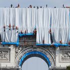 Workers unravel silver blue fabric, part of the process of wrapping L'Arc de Triomphe in Paris on September 12, 2021, designed by late artist Christo. - Work has begun on wrapping the Arc de Triomphe in Paris in silvery-blue fabric as a posthumous tribute to the artist Christo, who had dreamt of the project for decades. Bulgarian-born Christo, a longtime Paris resident, had plans for sheathing the imposing war memorial at the top of the Champs-Elysees while renting an apartment near it in the 1960s. (Photo by Thomas SAMSON / AFP) / RESTRICTED TO EDITORIAL USE - MANDATORY MENTION OF THE ARTIST UPON PUBLICATION - TO ILLUSTRATE THE EVENT AS SPECIFIED IN THE CAPTION