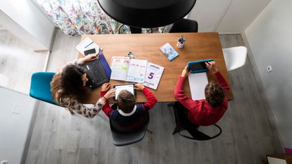 Una madre ayuda a sus hijos con los deberes mientras teletrabaja en un municipio de la Comunidad de Madrid.
