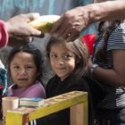 Dos niñas mexicanas hacen fila para conseguir su merienda, compuesta de plátanos y pan.