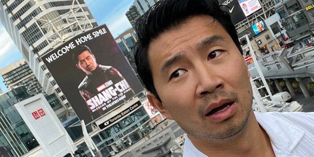 Simu Liu posa con una enorme cartelera de Shang-Chi en su ciudad natal