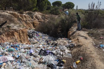 Un joven subsahariano lanza una bolsa de basura al vertedero del asentamiento El Bosque, en Lucena del Puerto. 
