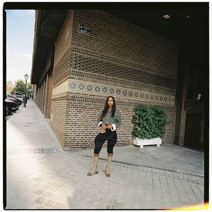 En esta imagen, con chaqueta Herringbone en terciopelo negro en contraste con puños blancos de algodón, pantalones de montar negros con logo, botas de lona y piel con estampado de doble G y riñonera, todo de Gucci.