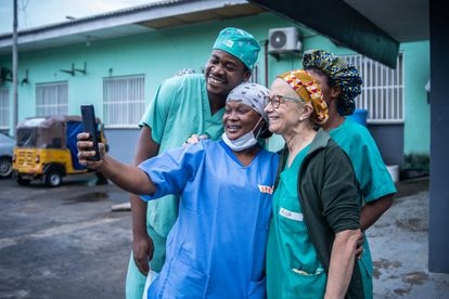 Tras la última operación, batas blancas, y uniformes verdes y azules salen por la puerta para sacar una foto grupal junto al cartel del hospital. Después, selfis para el recuerdo.