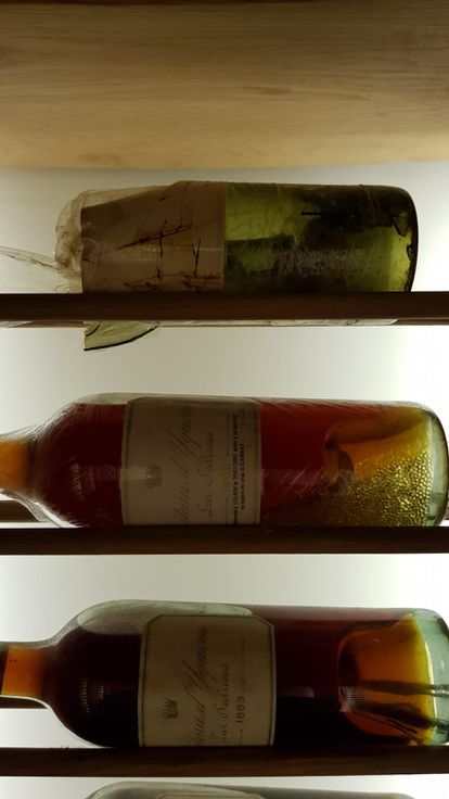 Arriba, la botella original de Chateau d’Yquem de 1806, rota tras un incidente en su almacenaje en 2001. Abajo, el vino recuperado en otra botella que ha sido sustraído de la bodega y que contiene unas perlas en su interior a modo de relleno del vino que fue derramado.
