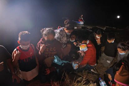 Familias ecuatorianas rezan después de cruzar el río Grande desde México, el 14 de abril en Roma, Texas.