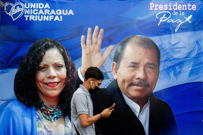 Un hombre camina delante de un cartel de propaganda que muestra al presidente de Nicaragua, Daniel Ortega, y la recién nombrada 'copresidenta' Rosario Murillo.