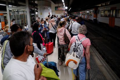 Decenas de pasajeros esperan en la estación de Sants en Barcelona la llegada de algún tren.