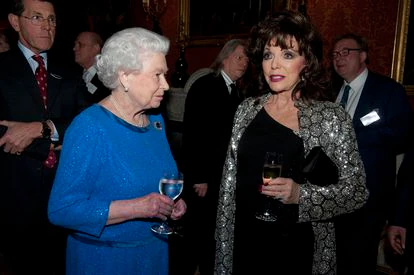 La reina Isabel II charla con la actriz Joan Collins en una recepción en el palacio de Buckingham, en Londres, en febrero de 2014.
