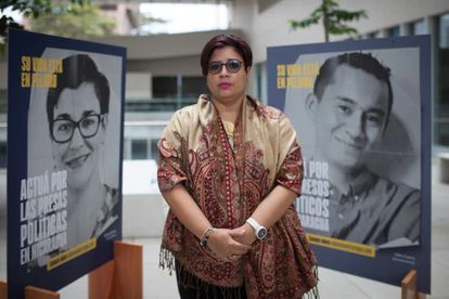 Edipcia Dubón posa frente a carteles de presos políticos en un evento sobre Nicaragua.