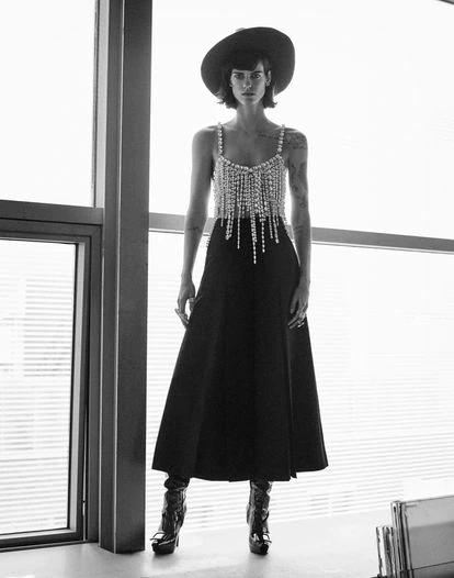 Los límites entre la joyería y la costura —y sus técnicas respectivas— se diluyen en piezas como este top de flecos de cristal que acompaña unos pantalones de lana plisados, ambos de Alexandre Vauthier. Sombrero bicolor blanco y negro en fieltro de conejo de Tolentino Hats, y botas altas Viv’ Choc en piel acharolada negra, con plataforma, tacón de aguja y hebilla lacada, de Roger Vivier. Pendientes de diamantes de Suot Studio y anillos 'vintage'.