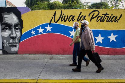 Dos ciudadanos caminan frente a un mural cera de un colegio electoral, el domingo en Caracas.