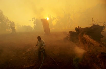 Un hombre con una mangera intenta hidratar el campo, en un rancho de California (Estados Unidos).