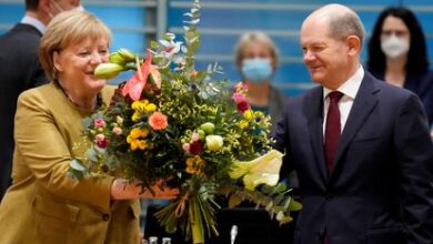 La canciller alemana en funciones, Angela Merkel, recibe un ramo de flores de su previsible sucesor, Olaf Scholz, esta mañana antes del que probablemente sea su último consejo de ministros.