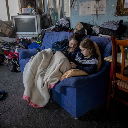 A woman rests with her daughter inside their home at the Canada Real shanty town, outside Madrid, Spain, Tuesday, Jan. 12, 2021. Shops are flimsy set-ups with little stock and the residents live off construction jobs, scrap metal collection or whatever they can, and the area has long been associated with drugs. (AP Photo/Manu Fernandez)