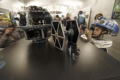 Un niño disfrazado de R2D2 observa unas figuras de Lego de 'Star Wars'.