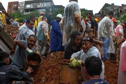 Ciudadanos ayudan este lunes a los bomberos a retirar barro en busca de desaparecidos por las fuertes lluvias en Franco da Rocha, en el Estado de São Paulo.