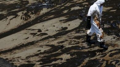 A worker walks following an oil spill caused by abnormal waves, triggered by a massive underwater volcanic eruption half a world away in Tonga, at the Peruvian beach in Ventanilla, Peru, January 18, 2022. REUTERS/Pilar Olivares