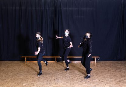 Tres alumnas bailan claqué en una clase.