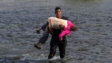 Un migrante venezolano carga una mujer para cruzar el Río Bravo en Coahuila, México.