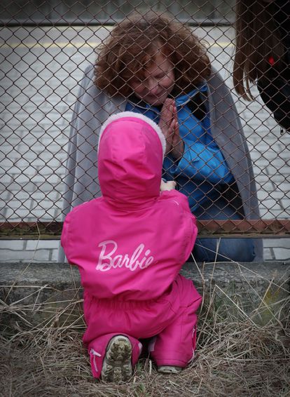 Una niña habla con su abuela tras la verja de la estacion de Przemysl, Polonia.