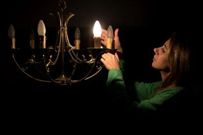 Una mujer quita una bombilla para reducir el consumo, en su vivienda en Madrid.