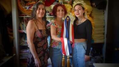 Ingrid Albornoz (izquierda), Marta Gatica y Arety Alvarado, integrantes del Sindicato Revolucionario Textil, muestran la banda que han confeccionado para el presidente Gabriel Boric, el 9 de marzo de 2022 en Santiago de Chile.