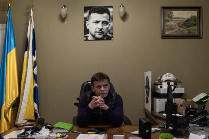 Serhii Sukhomlin, alcalde de Yitómir, el miércoles, en su despacho bajo una fotografía del presidente ucranio, Volodímir Zelenski, y con su fusil Kaláshnikov encima de su escritorio.