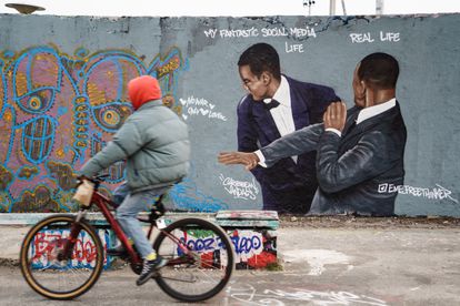 Un ciclista pasa, el 1 de abril, por un mural pintado en una calle de Berlín que escenifica el bofetón de Will Smith a Chris Rock. La obra es del artista dominicano Jesús Cruz Artiles.  