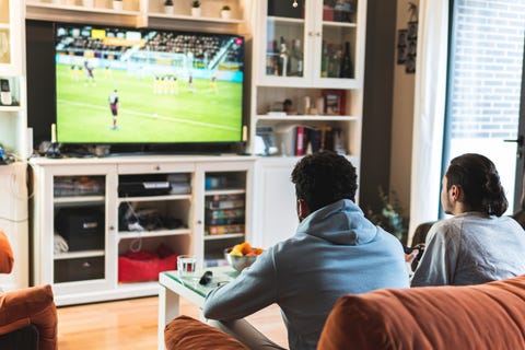 Jóvenes amigos varones jugando fútbol en la televisión en la sala de estar en casa jóvenes amigos varones jugando fútbol en la televisión en la sala de estar en casa