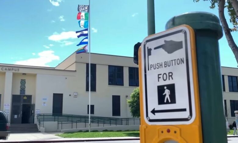 mujer baja del asta banderas de países latinos izadas en una escuela en Oakland