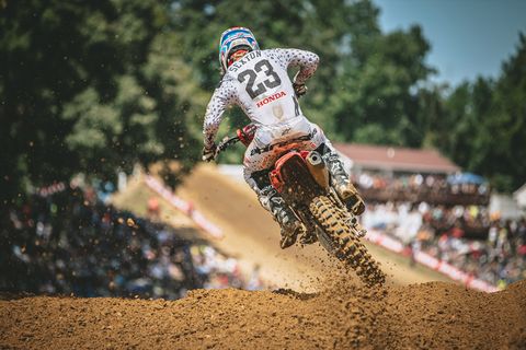 chico en un motocross rasgando una colina de barro