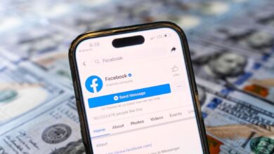 Facebook is shown on a smartphone in front of a background with 100 dollar bills