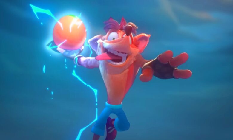 Image from the Crash Team Rumble trailer featuring Crash Bandicoot holding a Wumpa fruit encased in lightning as if he's about to slam dunk it into a basket. While wearing his trademark pants and his tongue hanging out.