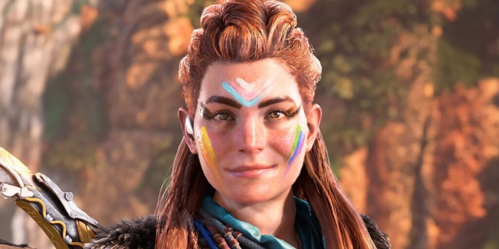 Horizon Forbidden West's Aloy smiles at the camera, as her face has paint markings that celebrate the LGBTQIAP+ community.