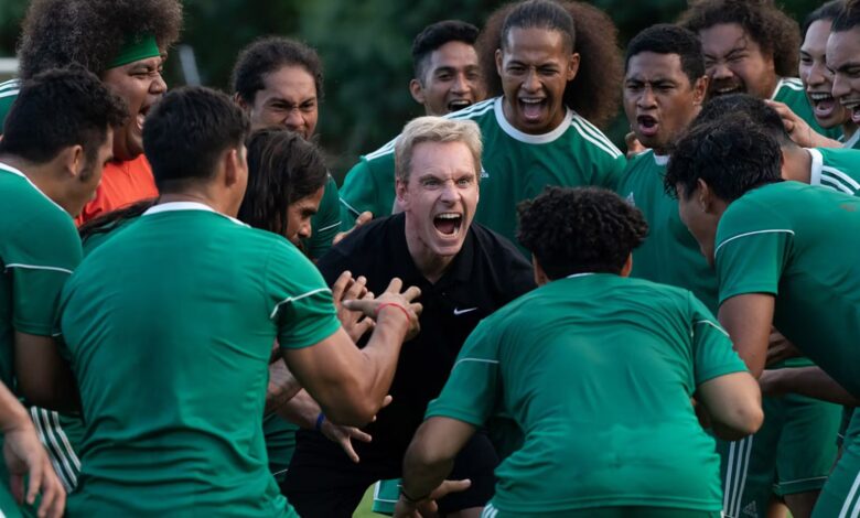 Michael Fassbender as Thomas Rongen yelling and surrounded by team in Next Goal Wins