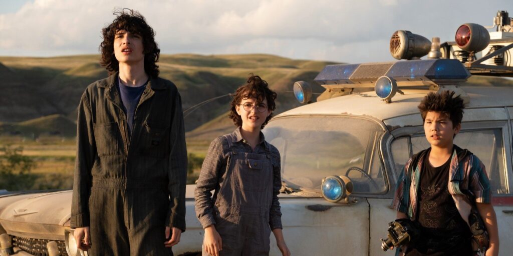 Trevor, Phoebe, and Podcast stand in front of the car in Ghostbusters: Afterlife