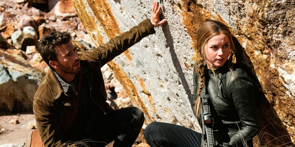 Chris Evans as Cole Turner and Ana de Armas as Sadie Rhodes hiding against rock in Ghosted