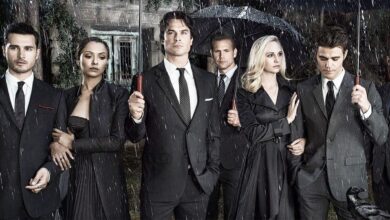 The Vampire Diaries cast wearing black and holding umbrellas in the rain