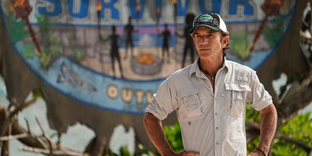 Jeff Probst - Survivor 44 wearing baseball cap in front of outlast logo