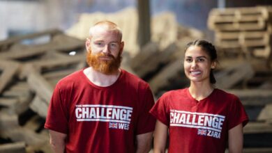 Zara Zoffany standing beside Wes Bergmann on The Challenge: World Championship. They are wearing red shirts with The Challenge logo and the UK flag. They are standing against a backdrop of debri in a warehouse.