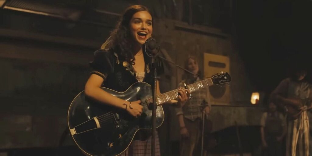 Rachel Zegler playing guitar and singing