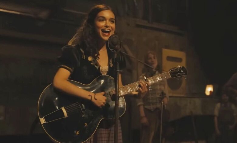 Rachel Zegler playing guitar and singing