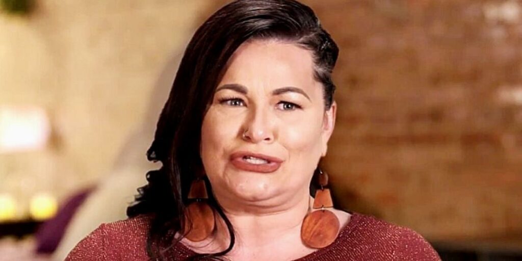 Molly Hopkins from 90 Day Fiancé talking to cameras in a brown shirt and earrings
