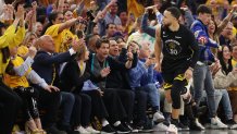 Stephen Curry #30 of the Golden State Warriors celebrates after making a basket as actor Rob Lowe reacts.
