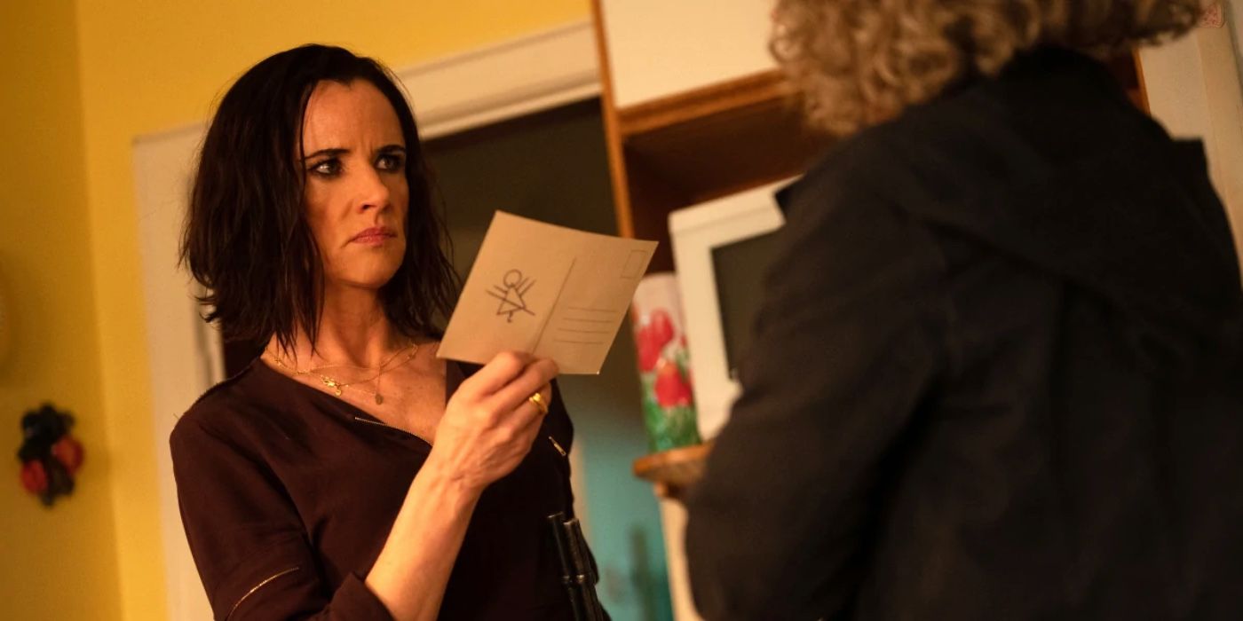 Natalie holding a postcard with the mysterious symbol on Yellowjackets